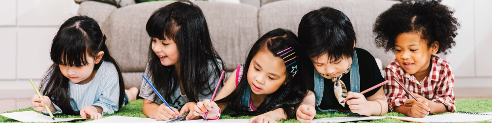 children on the floor writing in notepads